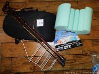 Two folding canes, Sleep Buddy leg pillow, Obus Ultra Forme chair pillow, and white metal shower caddy on wooden floor