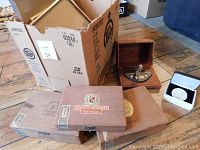 Three wooden cigar boxes stacked and a wooden display case with brass beaver award on wooden floor.
