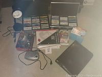 Wide shot showing all items including two cases of cassette tapes, alarm clock radio, desk lamp, zippered binder case, office supplies, and floor savers