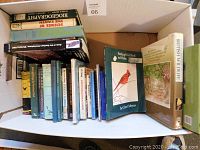 Box containing about 25 various hardcover and paperback books focusing on nature, wildlife, bird feeding, and biology topics, neatly arranged showing titles and authors.