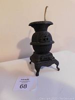 Full view of the miniature cast iron pot-bellied stove, showing the top pipe, rounded body and curved legs.