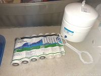 Sealed set of seven Watts RO filters with white RO pressure tank and white plastic RO wrench.