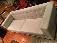 Photo showing the modern neutral grey sofa with tufted button design on backrest and seat cushions.