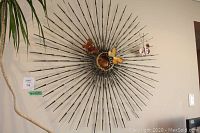 Front view showing full large circular metal wall decor with radial metal rods and three metal butterflies attached near center.