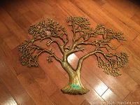 Full frontal view of the solid brass tree wall artwork on wooden floor, showing the full shape and branching design.
