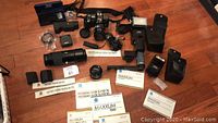 Full overview of Minolta 7000 Maxxum camera set including camera, lenses, flashes, manuals, straps, and accessories arranged on floor.