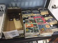Photo of a box containing numerous View-Master reels in paper sleeves and several colorful booklets