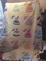 Full view of the full-size quilt showing multiple Sunbonnet Sue pattern blocks in various pastel and bright colors, bordered by a pale yellow quilted border.