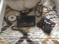 Garmin GPS device, adapter cable, and power adapter shown from front and side angles.