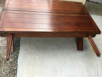 Photo of the folded wood coffee table tabletop and legs showing scratches and wear.