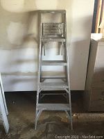 Front view of 5 foot aluminum step ladder showing five steps and wear marks