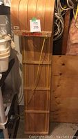 Full length view of wood torpedo toboggan with front curved edge, label with lot number, rope attached.
