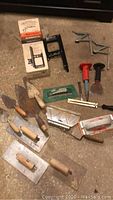 Overview of various trowels, chisels, adhesive spreaders, sanding block and Black & Decker guidemate.