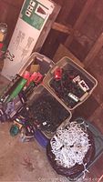 Three plastic tubs filled with various holiday lights and light accessories placed beside tree box in storage area.