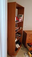 Side view of tall teak wood shelving unit showing slim depth and flat finish surface