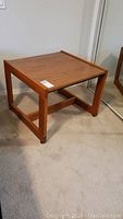 Full view of the square teak wood end table showing wood grain laminate top and frame.
