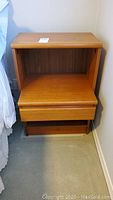 Full view of the teak night stand showing the top surface, open shelf, cantilevered drawer, and bottom open compartment.
