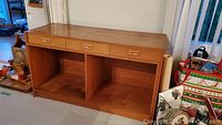 Front view of teak buffet showing three top drawers and two lower open compartments