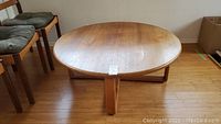Full front view of round teak cocktail table showing pedestal base