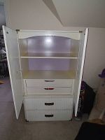 Open view of white armoire showing two shelves and two inner drawers inside the cabinet space, plus three drawers below the doors.