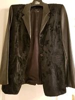 Front view of the black women’s blazer with leather sleeves and fur front panel hung on a hanger.