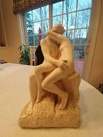 Full frontal view of the statue placed on a countertop with a window and outdoor scene in the background showing the detailed figures and textured base.