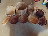 Ten assorted straw baskets of various sizes, shapes, and colors shown on a floor, depicting condition and variety of weave patterns.