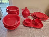 Multiple red Fiesta pieces displayed on table: teapot, sugar bowl, creamer, tray, bowls and plates