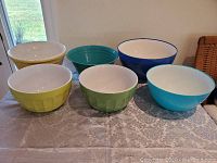 Six large mixing bowls arranged on a table showing variety of glass and plastic materials and colors.