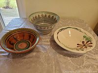 Photo showing three pottery bowls with different decorative patterns arranged on a table.