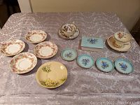 Full lot with teacups, saucers, coasters, and trinket box laid out on table