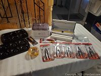 Full view of lot items including vacuum sealer, yogurt maker jars, seafood fork sets, baking sheets, and serving plates