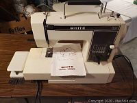 Full view of White Model 1033 sewing machine on wooden surface with instruction booklet on top.