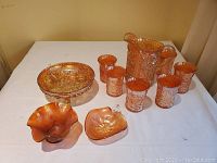 Full overview of the lot showing the large pitcher, six glasses, a footed dish, and two candy dishes on a white table.