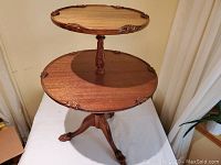Full view of the two-tier round wooden dessert table highlighting both tiers and the three claw legs.