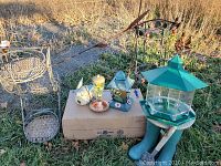 Lot laid out on grass shows all items including bird feeders, flower stands, and garden decor.