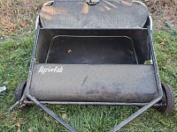 Front view of black metal push lawn sweeper with collection hopper featuring Agri-Fab logo.