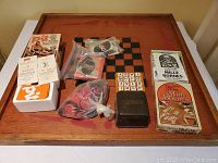 The full collection of games displayed on a wooden game board table, showing multiple card decks, game rule booklets, and boxed games.