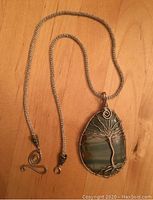 Full view of the pendant necklace showing the entire silver-colored woven chain and pendant.