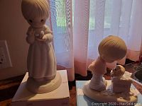 Front view of girl figurine holding a dove standing on original box, showing detailed features and colors.