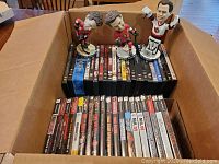 Box contents showing multiple PlayStation 2 game cases and DVDs with three Senators bobbleheads on top