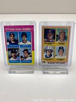 Front side of both cards in protective sleeves showing the group shots of players from each card.