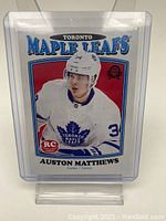 Front of 2017 O-Pee-Chee hockey card #694 showing Auston Matthews in Toronto Maple Leafs uniform with Rookie Card logo.