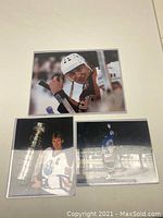 Top view of three Wayne Gretzky photos showing close-up of his face on bench, Stanley Cup photo, and skating on ice photo.