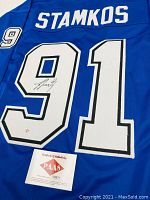 Angled close-up of back number and certificate card showing stitching detail and COA label.