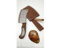 Cleaver with handle, leather sheath, and protective cover laid out with some accompanying small wooden piece.