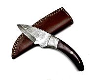 Handcrafted Damascus steel hunting knife with curved wood handle placed on top of a brown stitched leather sheath, shown blade side up.