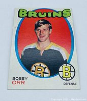 Front photo showing Bobby Orr in Bruins uniform with colorful border, team name, and player position.