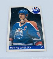 Front of 1985 O-Pee-Chee Wayne Gretzky #120 hockey card in Edmonton Oilers uniform, from shoulders up, showing wear and creases.