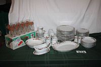 Photo showing the full collection of holiday-themed dinnerware and glasses arranged on a green cloth.